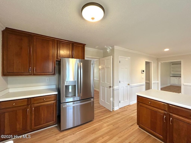 kitchen featuring light wood-type flooring, crown molding, stainless steel refrigerator with ice dispenser, and light countertops