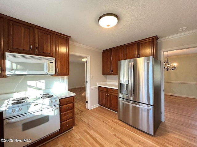 kitchen featuring crown molding, a chandelier, light countertops, light wood-style floors, and white appliances