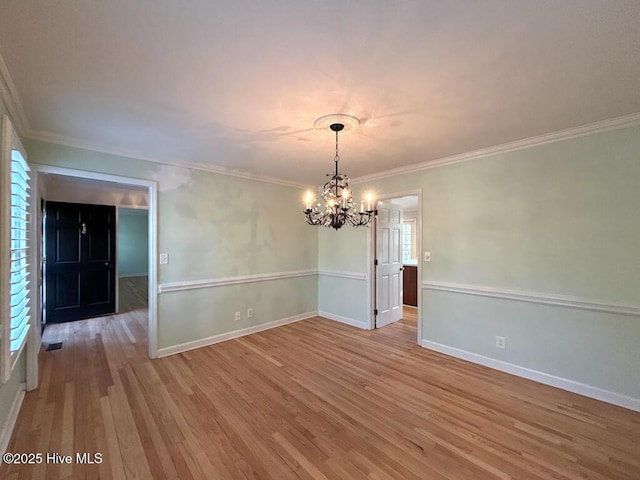 empty room with baseboards, a notable chandelier, wood finished floors, and crown molding