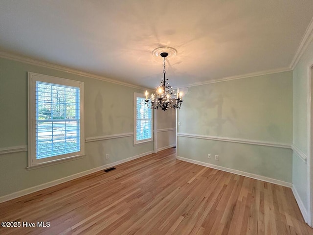 spare room featuring baseboards, visible vents, ornamental molding, light wood-type flooring, and a chandelier