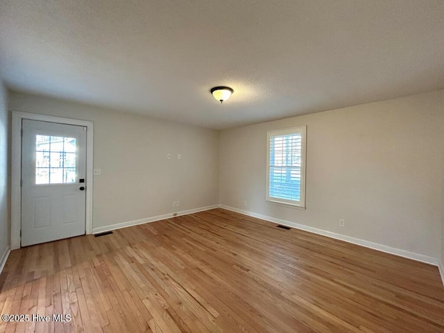 unfurnished room featuring plenty of natural light, visible vents, and light wood-type flooring