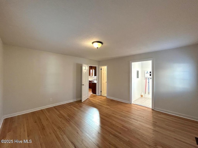 unfurnished bedroom with baseboards, light wood-type flooring, and connected bathroom