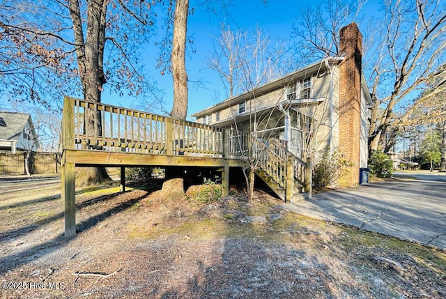 back of property featuring stairs, a wooden deck, and a chimney