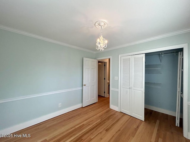 unfurnished bedroom featuring an inviting chandelier, crown molding, wood finished floors, and baseboards