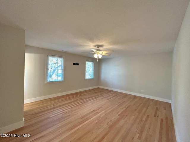 spare room with baseboards, a ceiling fan, and light wood finished floors