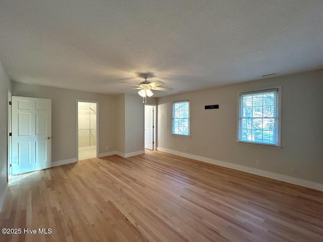 spare room featuring visible vents, baseboards, ceiling fan, light wood-style floors, and a textured ceiling