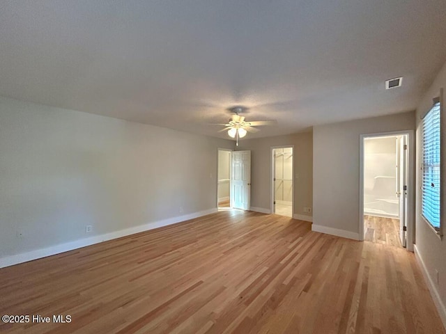 empty room featuring visible vents, light wood-style flooring, baseboards, and a ceiling fan