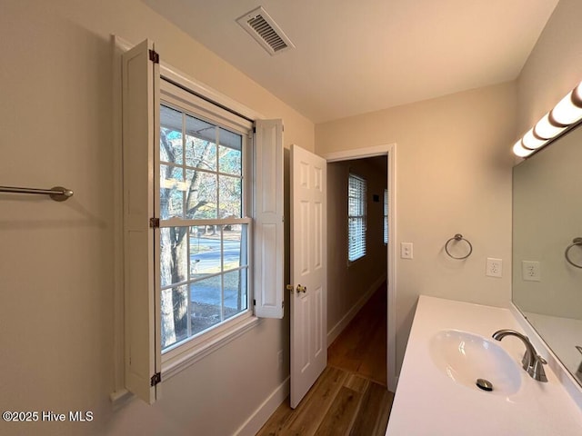 bathroom with visible vents, vanity, baseboards, and wood finished floors