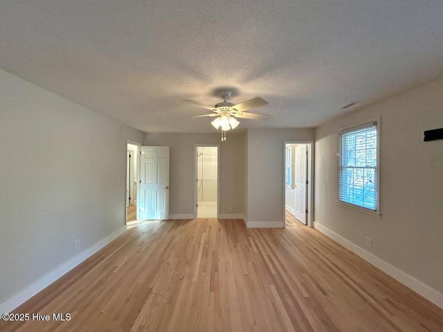 empty room featuring ceiling fan, baseboards, light wood finished floors, and a textured ceiling