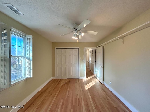 unfurnished bedroom featuring a textured ceiling, light wood-style floors, visible vents, and baseboards