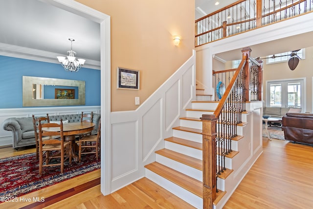 1807 Baywater Ct SE, Bolivia, NC 28422 - stairs with a chandelier, wood finished floors, a decorative wall, and a wainscoted wall