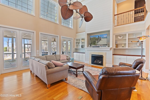 1807 Baywater Ct SE, Bolivia, NC 28422 - living room featuring light wood finished floors, a towering ceiling, french doors, a fireplace, and built in shelves