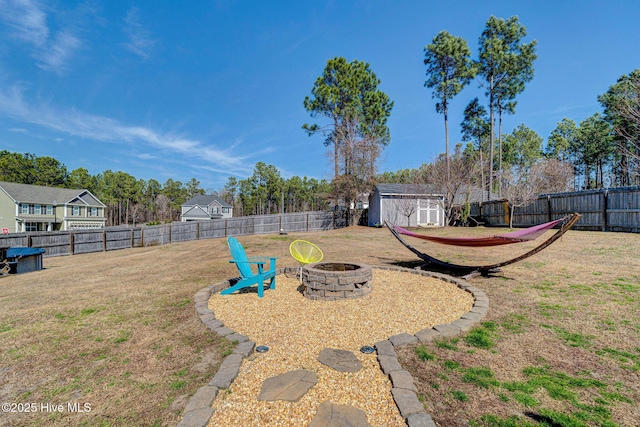 view of yard featuring an outbuilding, a fire pit, a storage shed, and a fenced backyard