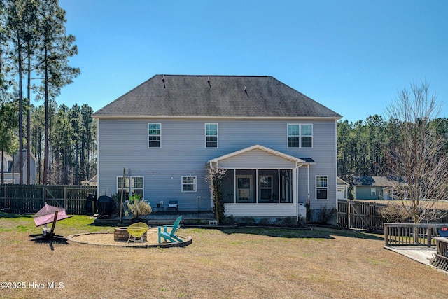 rear view of property with fence, an outdoor fire pit, a yard, a sunroom, and a patio area