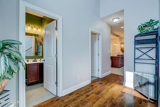 hallway featuring baseboards, light wood-style floors, and a sink