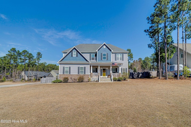 view of front of property with stone siding, covered porch, and fence