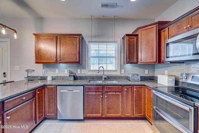 kitchen featuring visible vents, a sink, backsplash, dark stone counters, and appliances with stainless steel finishes