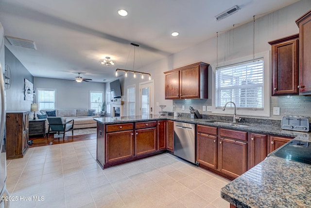 kitchen featuring visible vents, a sink, stainless steel dishwasher, a peninsula, and decorative backsplash