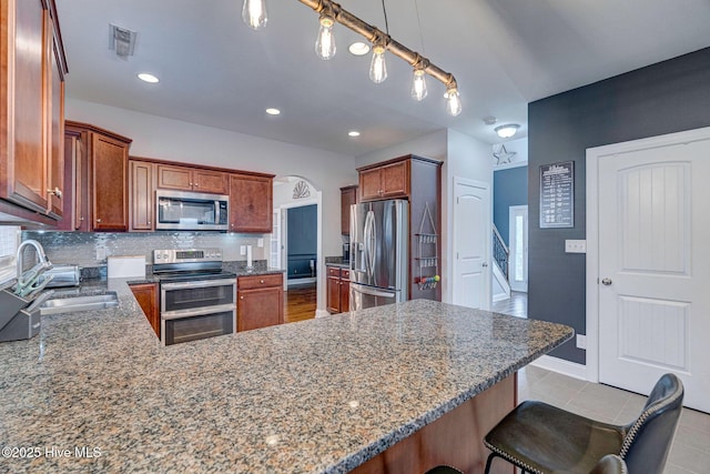 kitchen with visible vents, decorative backsplash, appliances with stainless steel finishes, a peninsula, and a sink