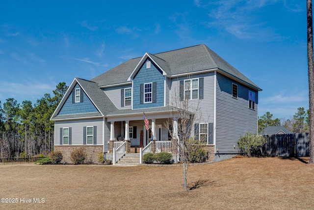 craftsman house with a porch, a front yard, and fence