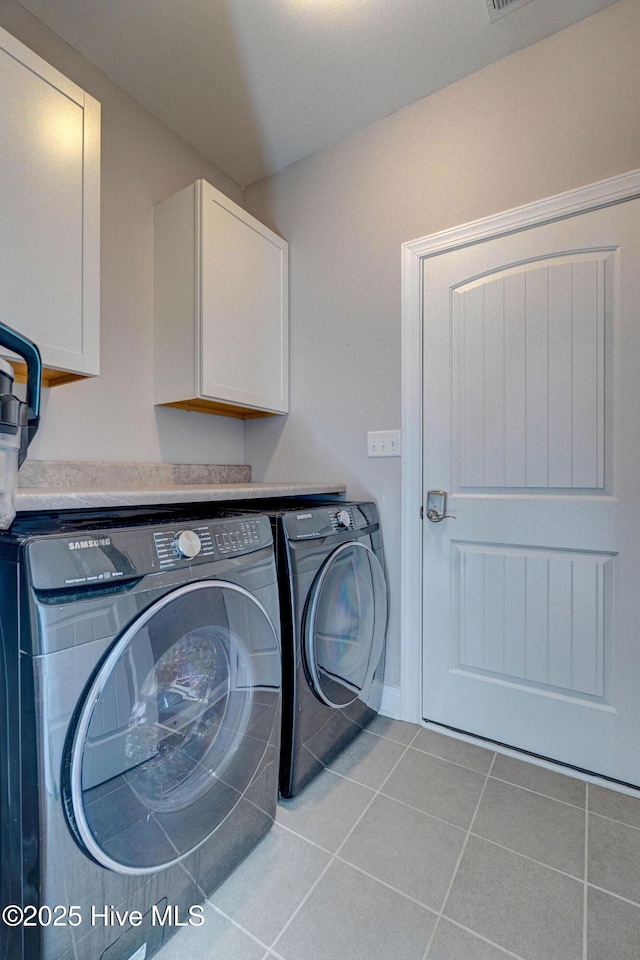 clothes washing area featuring cabinet space, tile patterned flooring, washer and dryer, and visible vents