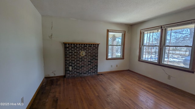 empty room with a textured ceiling, baseboards, and wood finished floors