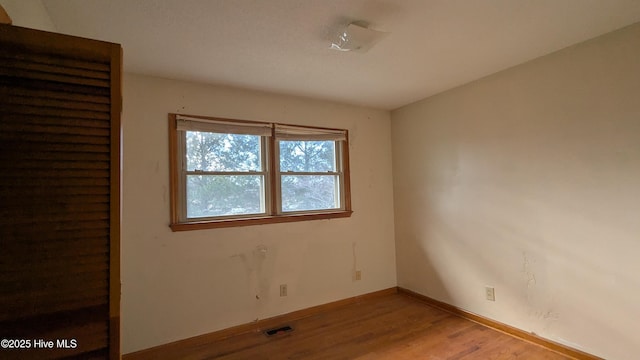 empty room featuring baseboards, visible vents, and light wood-type flooring