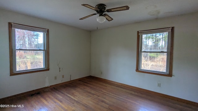 spare room featuring ceiling fan, visible vents, baseboards, and wood finished floors