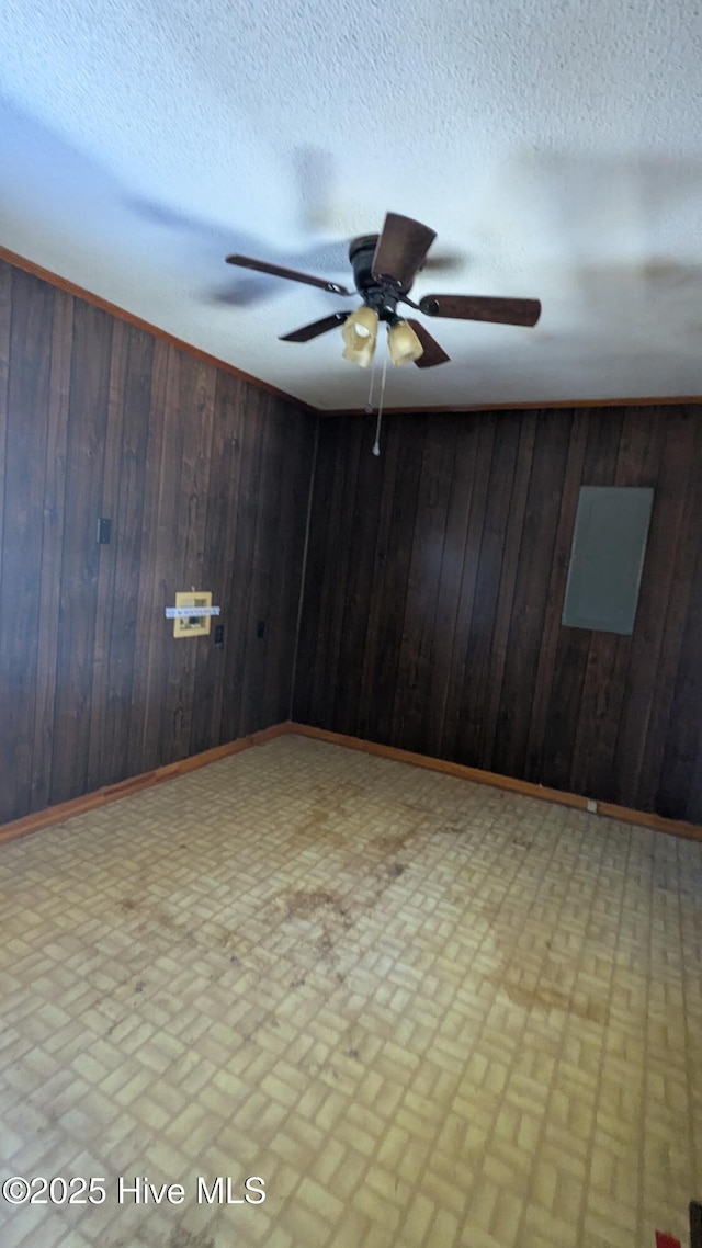 unfurnished room featuring wood walls, a textured ceiling, and baseboards