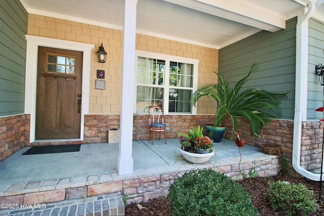 view of exterior entry featuring covered porch and stone siding