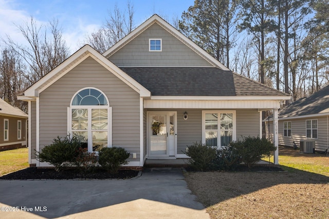 view of front facade featuring covered porch, central AC, and a shingled roof