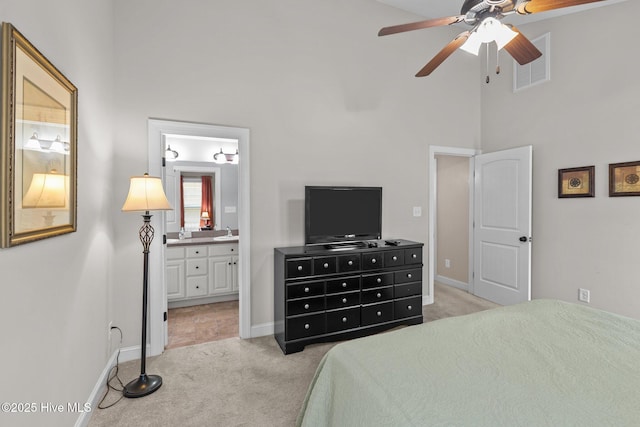 bedroom featuring visible vents, ensuite bath, a high ceiling, a sink, and light colored carpet