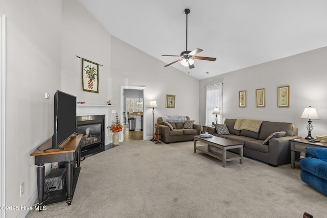 carpeted living room featuring baseboards, a fireplace with flush hearth, high vaulted ceiling, and ceiling fan