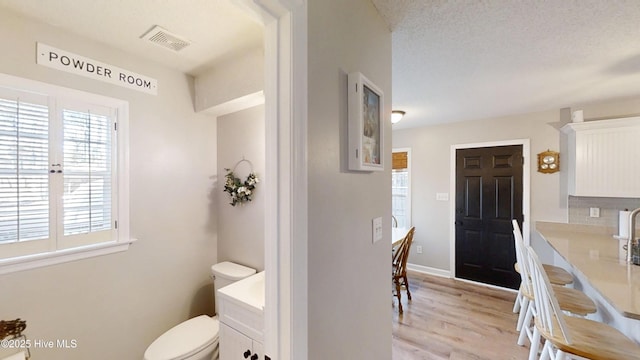 bathroom with visible vents, baseboards, toilet, wood finished floors, and vanity