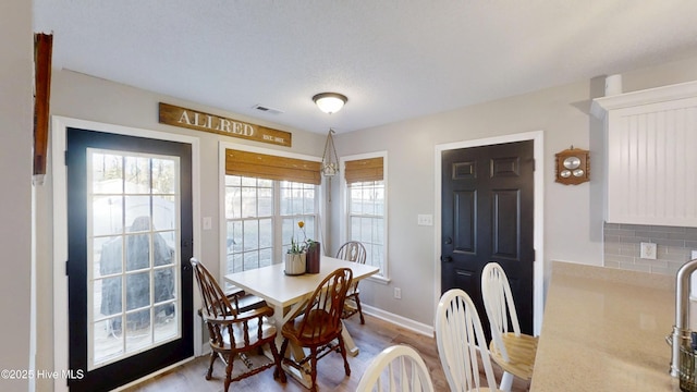 dining area featuring wood finished floors, visible vents, and baseboards