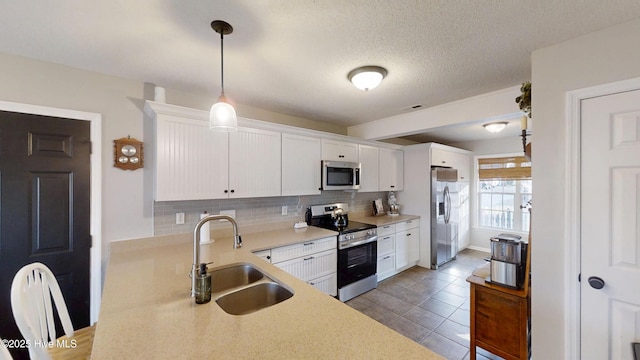 kitchen with a sink, backsplash, appliances with stainless steel finishes, and white cabinets