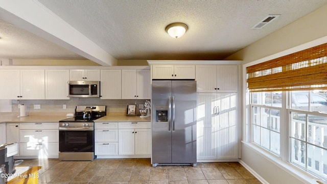 kitchen with visible vents, light countertops, white cabinets, appliances with stainless steel finishes, and backsplash