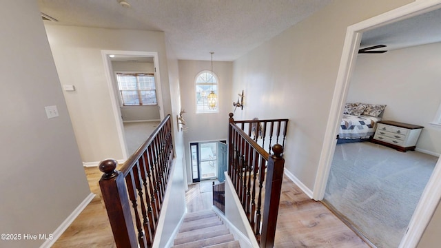 stairway featuring baseboards, a textured ceiling, and wood finished floors