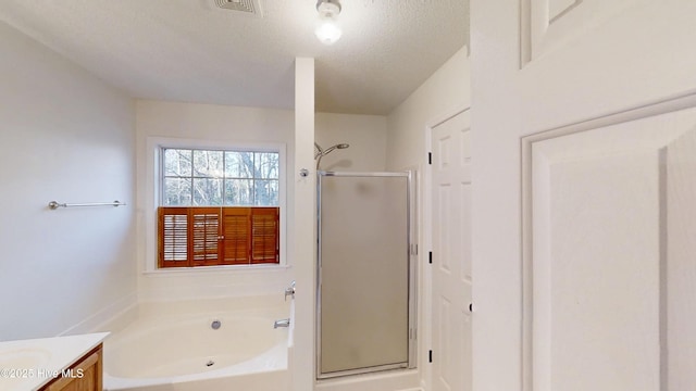 bathroom featuring vanity, a bath, a shower stall, and a textured ceiling