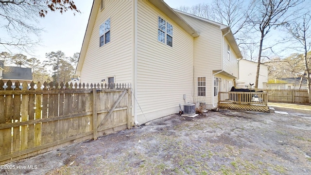 back of house with central AC unit, a deck, and fence