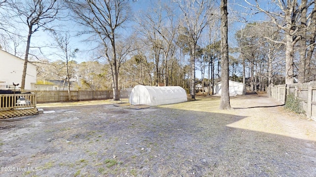 view of yard featuring a deck, an outdoor structure, and a fenced backyard