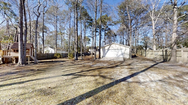 view of yard featuring an outdoor structure, a detached garage, fence, and dirt driveway