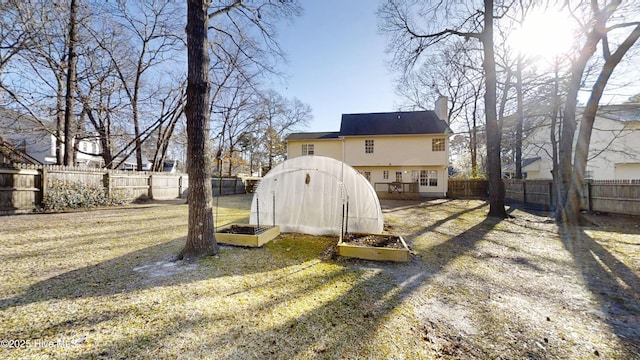 back of property featuring a garden, a fenced backyard, and a chimney