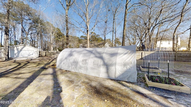 view of outbuilding with a garden, an outbuilding, and fence