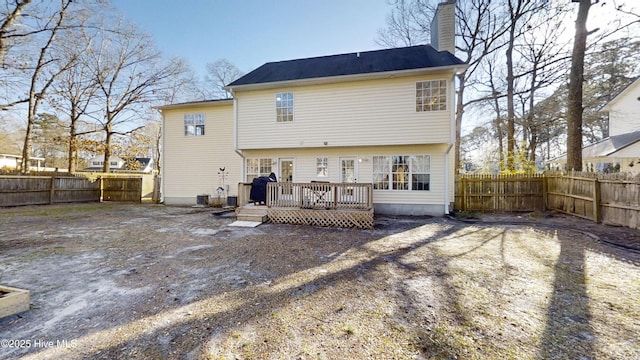 back of property with a fenced backyard, a chimney, and a wooden deck