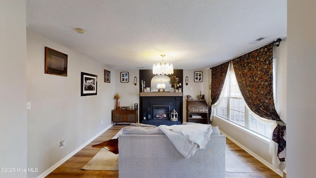 living room featuring a fireplace, wood finished floors, baseboards, and a chandelier