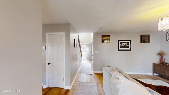 corridor featuring a textured ceiling, baseboards, and wood finished floors