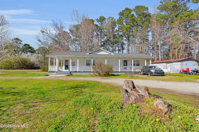 ranch-style home featuring covered porch, a front lawn, and dirt driveway