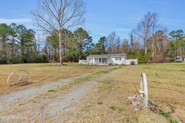 manufactured / mobile home featuring a front lawn and dirt driveway