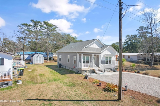 view of front facade featuring a shingled roof, a shed, a porch, crawl space, and an outbuilding